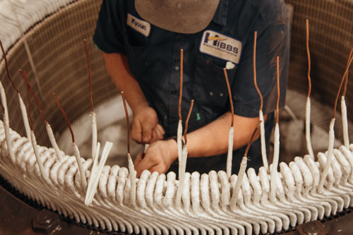 Hibbs technician winding a large coil from inside the motor